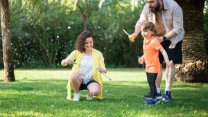 A family enjoys a playful day with bubbles in a sunny park setting.